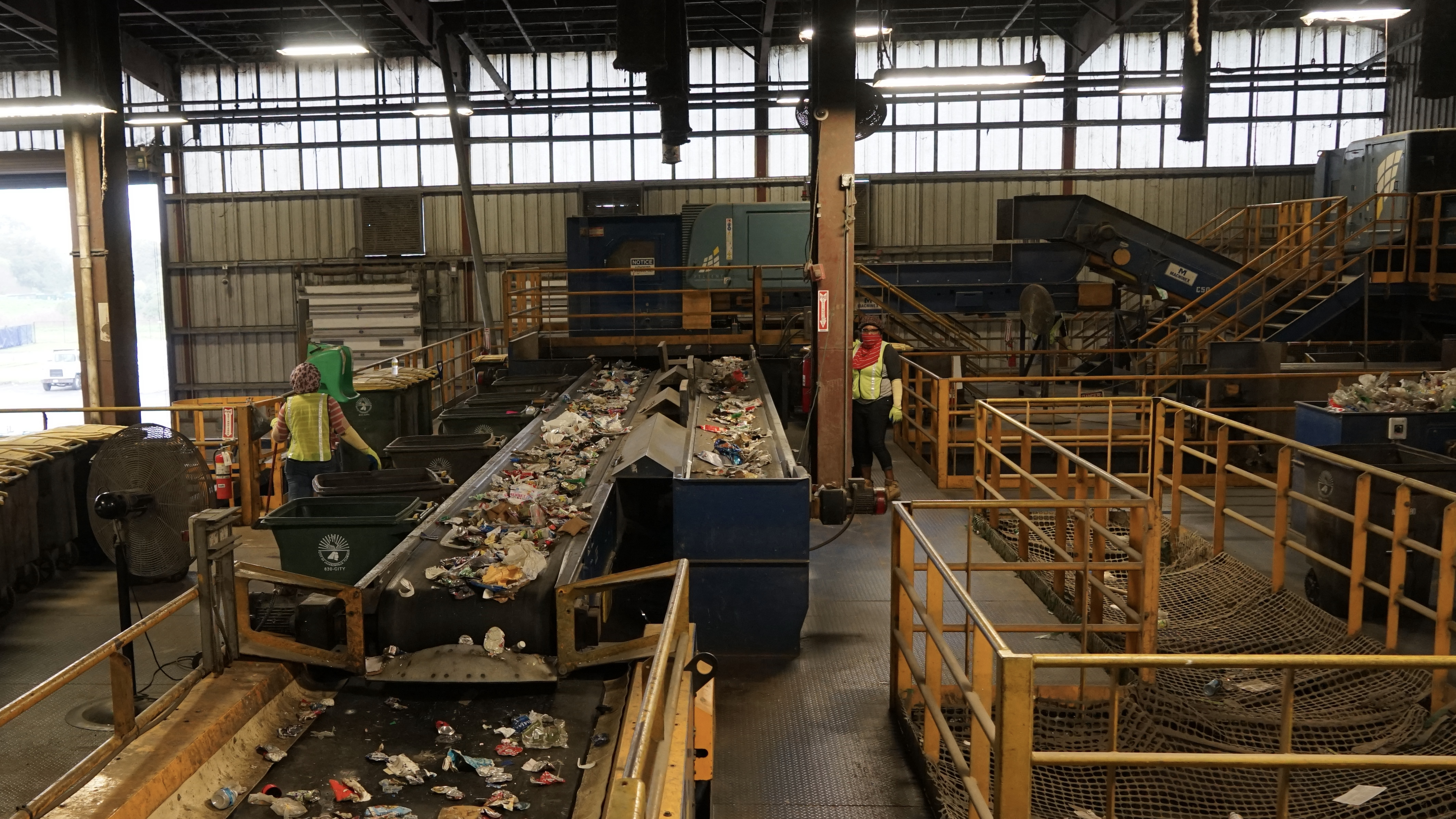 Two workers are sorting out materials at the recycling center